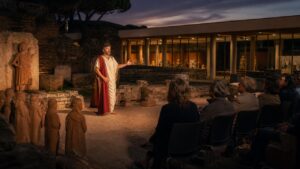 Attore in abiti ispirati all’antica Roma durante una rappresentazione teatrale tra reperti archeologici